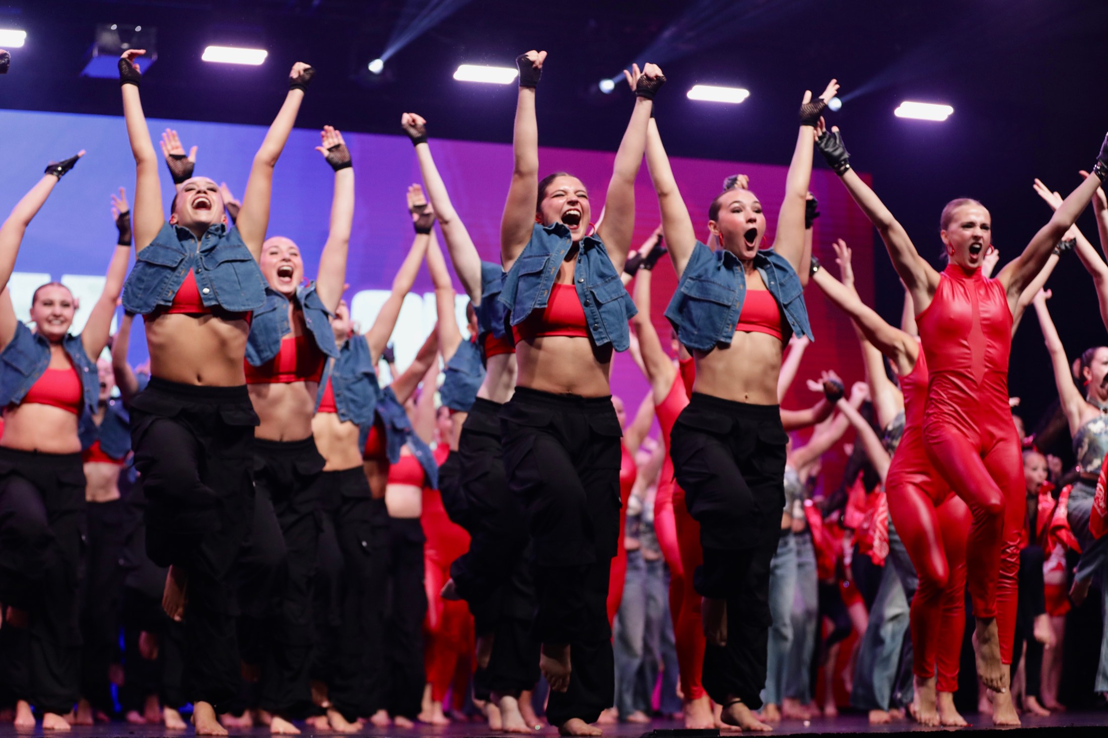 A line of dancers mid-jump with their arms raised