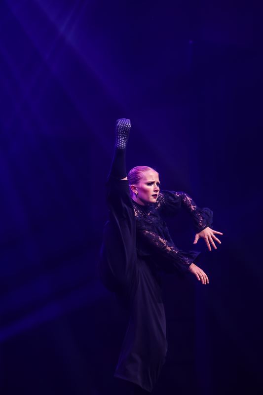 A soloist in a dark costume under a single spotlight