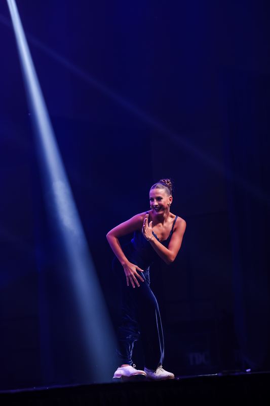 A soloist in streetwear caught in a spotlight beam